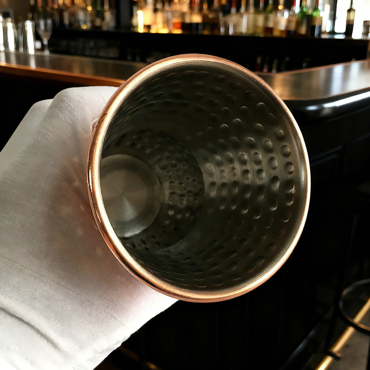 Gobelet tiki en inox cuivré, 350ml Nesty, gros plan de dessus sur l'intérieur martelé, posé sur une serviette blanche au bar