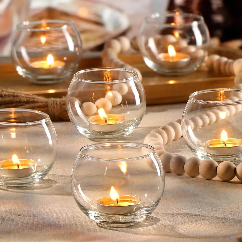 Photophores votifs en verre Nesty - Plusieurs photophores ronds en verre transparent avec bougies chauffe-plat allumées, guirlande de perles en bois sur la table