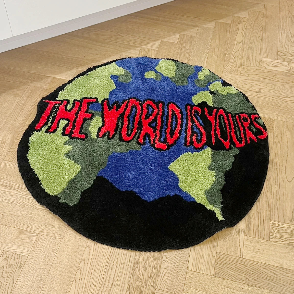 Tapis rond en acrylique — motif animalier - Nesty, vue en angle du tapis rond motif carte du monde sur un parquet clair