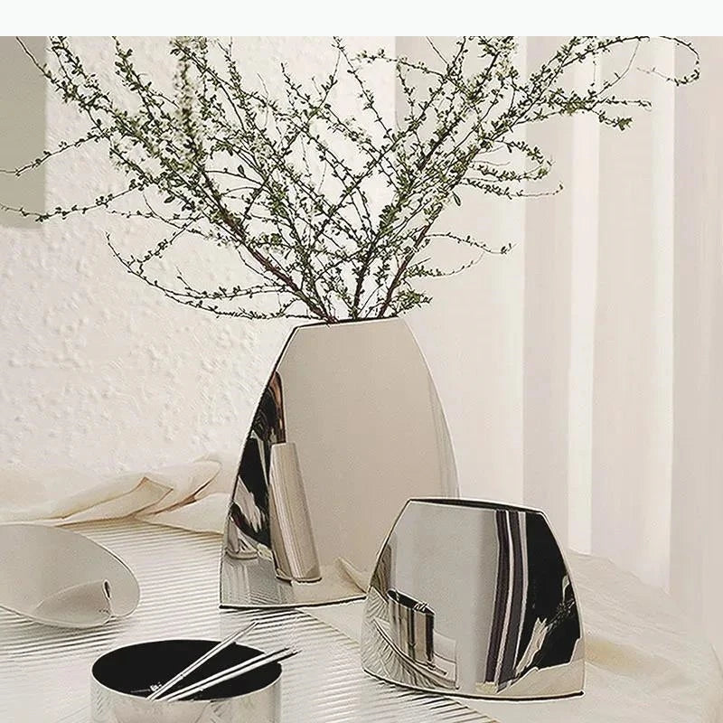 Vase arc en métal argenté — silhouette minimaliste - Nesty - Trois tailles avec branchages verts, sur table avec bol et pinceaux