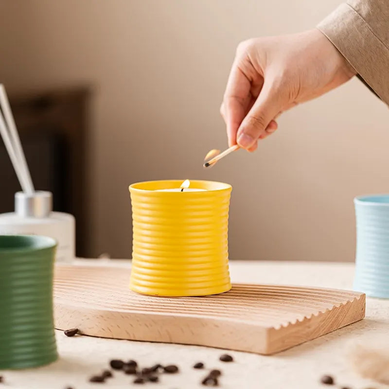 Photophore jarre en céramique striée Nesty - Modèle jaune avec bougie allumée à l'allumette, planche en bois et grains de café