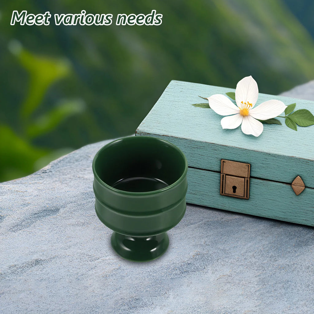 Plateau brûle-encens en céramique Nesty - Coupe vert foncé sur pied posée sur un rocher, avec coffret bleu pastel et fleur blanche