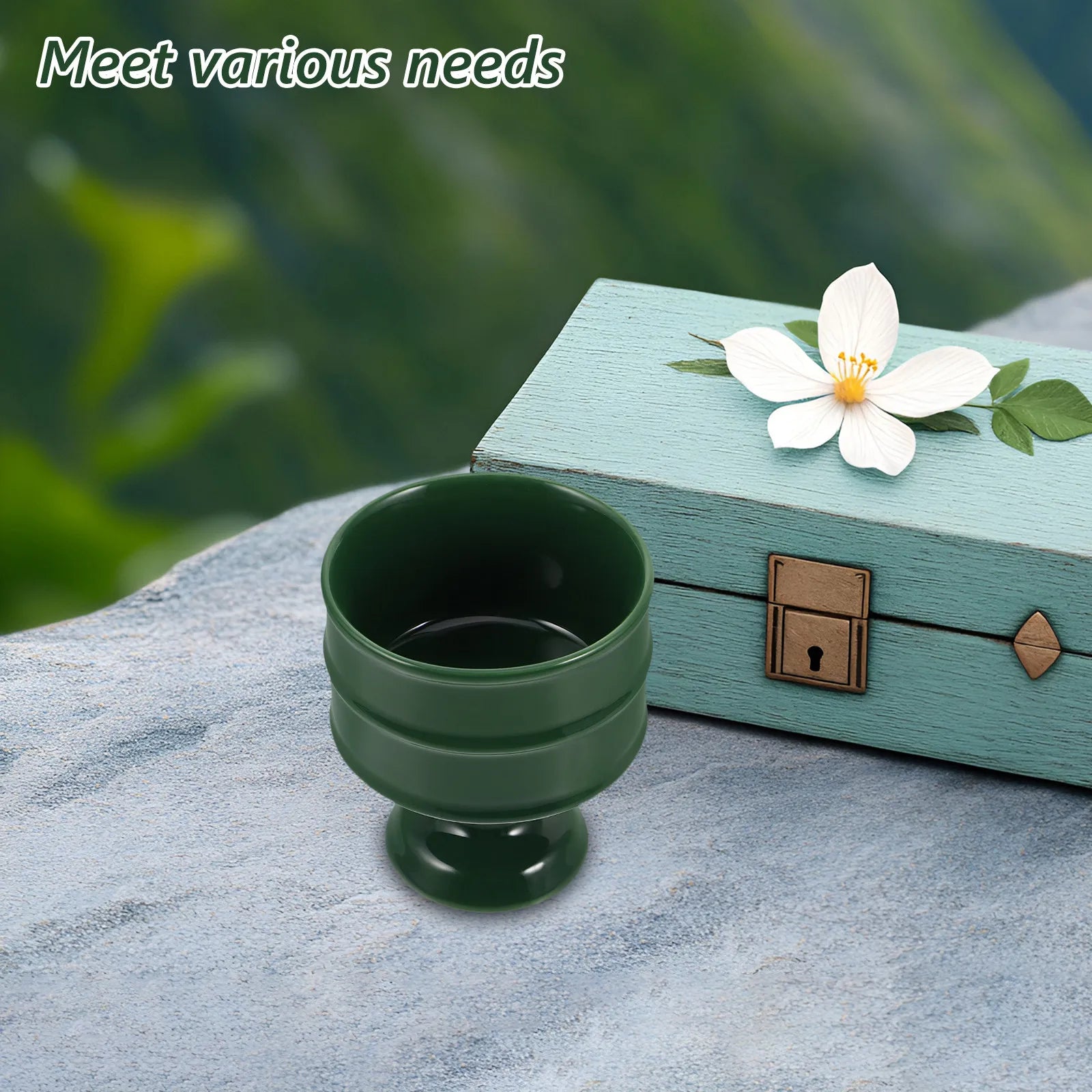 Plateau brûle-encens en céramique Nesty - Coupe vert foncé sur pied posée sur un rocher, avec coffret bleu pastel et fleur blanche