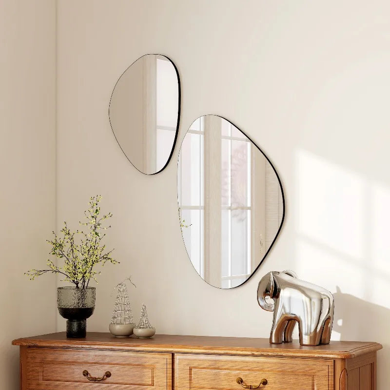 Duo de miroirs muraux galets à cadre noir fin, superposés en biais, au-dessus d'une commode avec vase et éléphant décoratif - Nesty