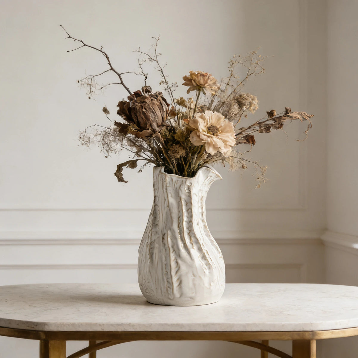 Vase en céramique texturiée blanc crème, esprit wabi-sabi japandi Nesty, garni de fleurs séchées brunes et beiges, sur console en marbre à pieds dorés