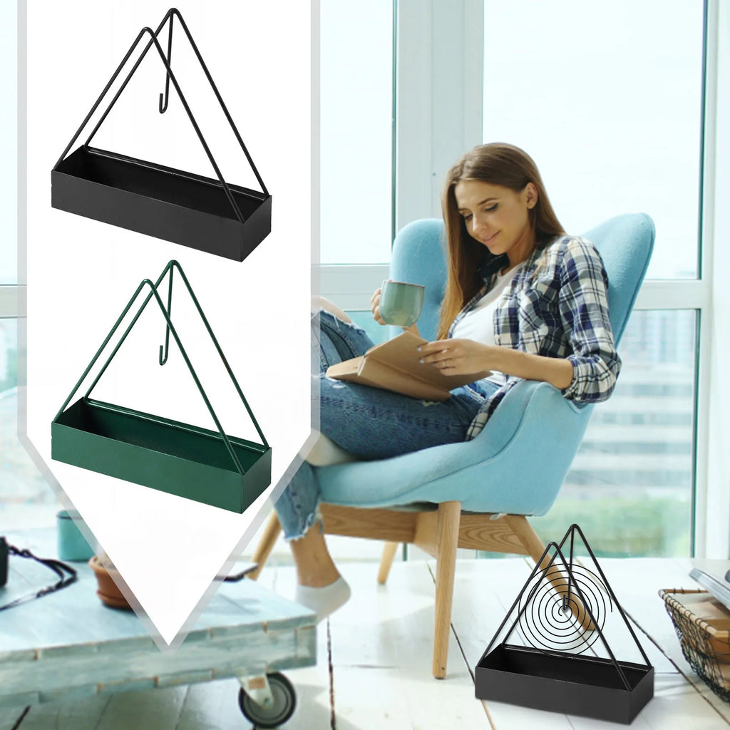 Porte-encens en inox Nesty - Coloris noir et vert, présentés avec une personne lisant