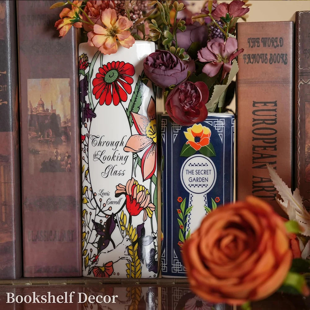 Vase en céramique en forme de livre, décoration pour bibliothèque Nesty, quatre vases individuels en forme de livre à couvertures illustrées différentes (fleurs roses, floral bleu marine, "Through the Looking Glass", "The Great Gatsby" doré), vus de face sur fond blanc