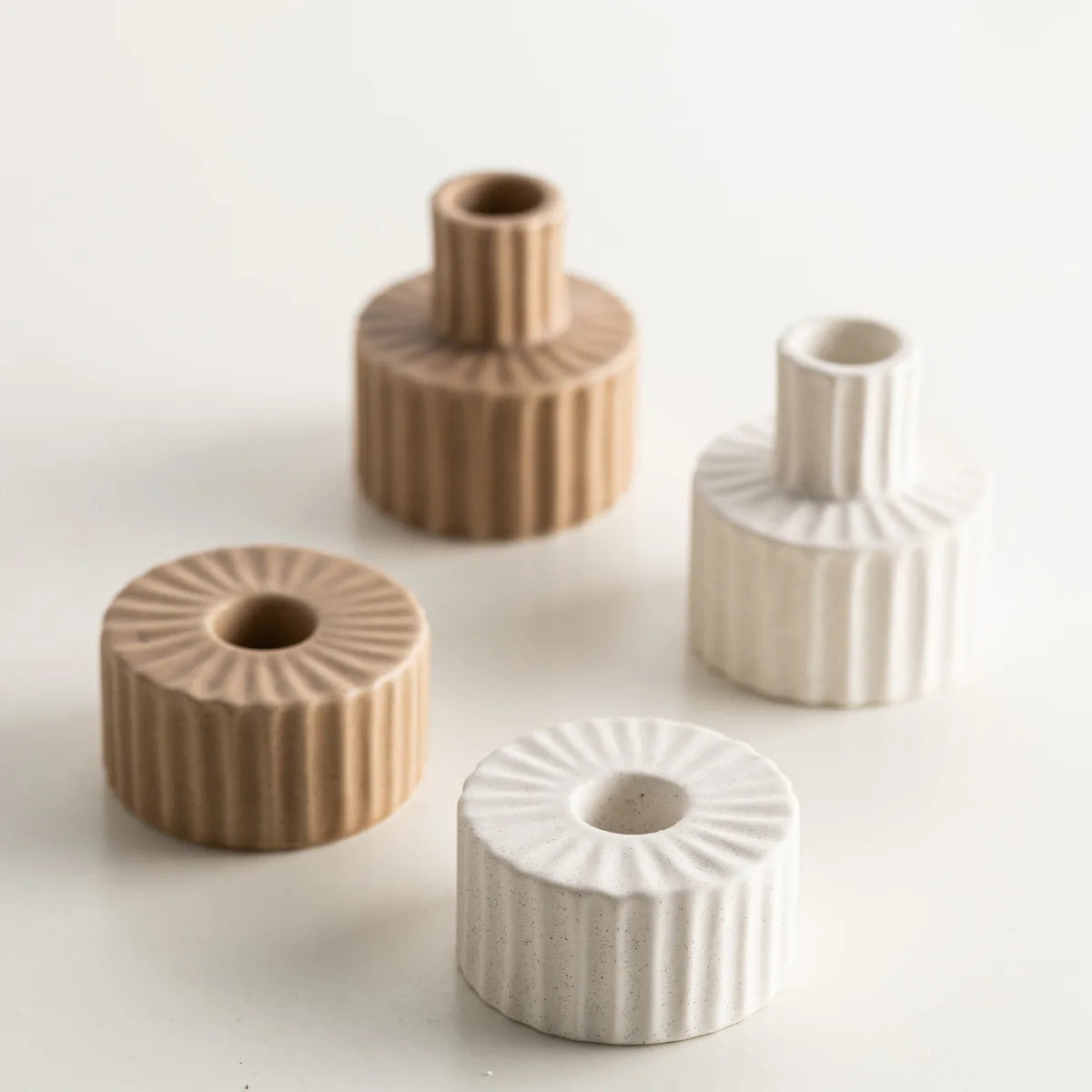 Quatre bougeoirs céramique nordique godronnés en coloris beige et blanc, deux hauts et deux plats, sur fond blanc - Nesty