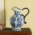 Vase en porcelaine bleu et blanc, motif ancien Nesty, pichet à motifs floraux et anse bleu foncé, posé sur un meuble en bois