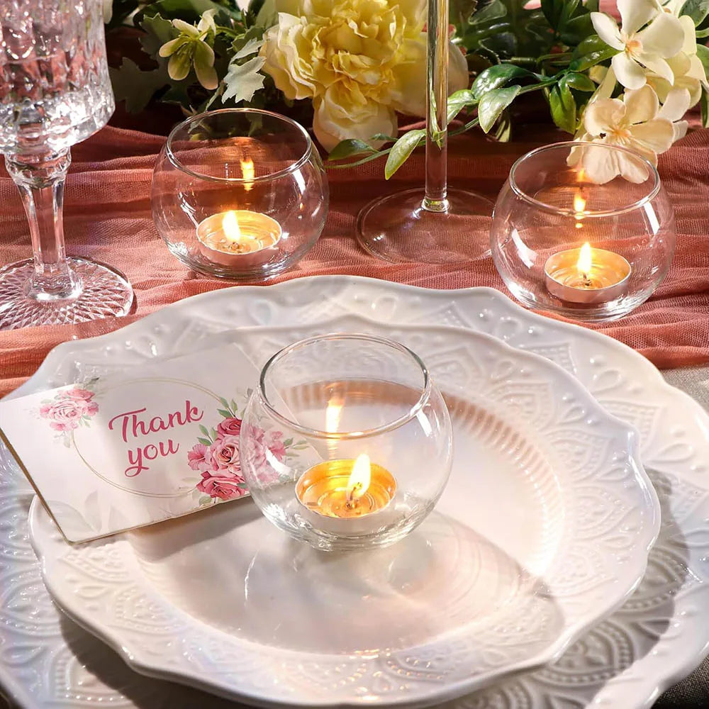 Photophores votifs en verre Nesty - Photophores ronds avec bougies allumées posés sur une assiette blanche avec une carte de remerciement et des fleurs