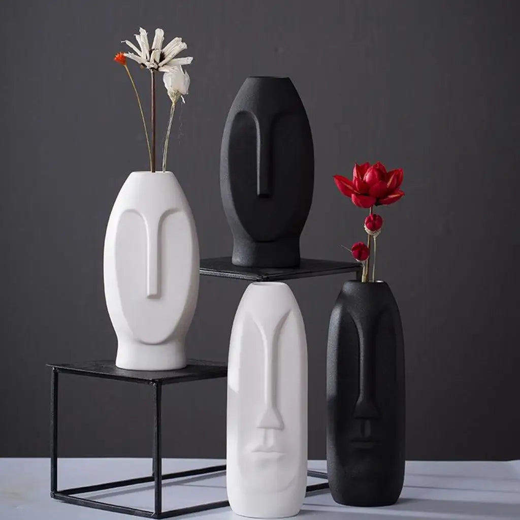 Vase visage en céramique Nesty - Quatre vases noirs et blancs sur étagères métalliques avec fleurs rouges et blanches