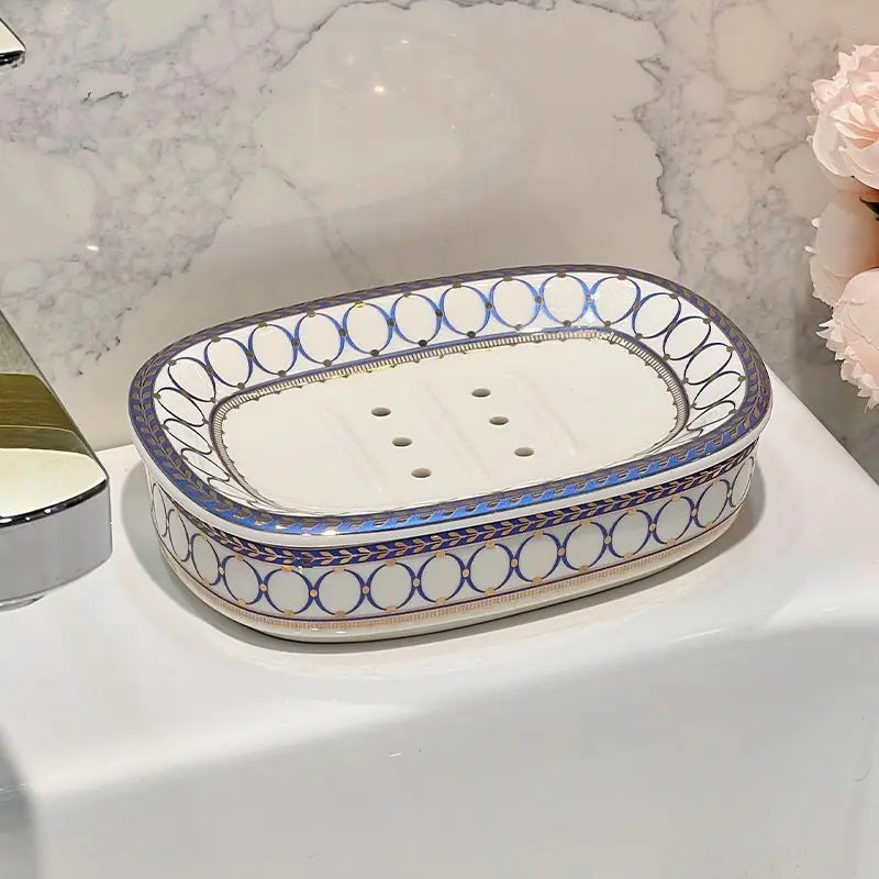 Porte-savon ovale en céramique à motif de cercles bleus et dorés, avec trous d'égouttage, sur un plan de vasque - Nesty