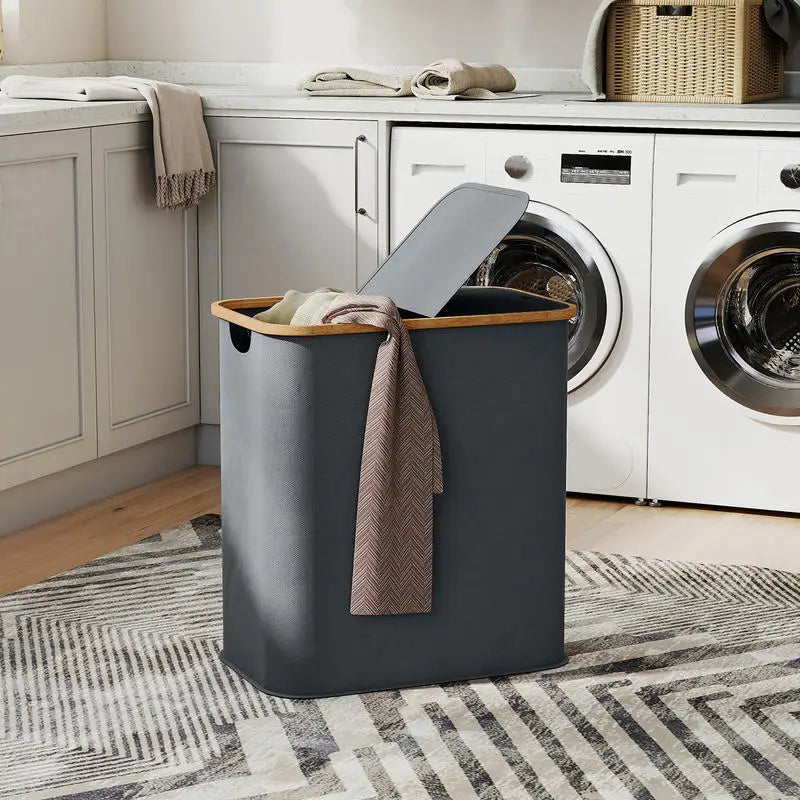 Panier à linge pliable gris Nesty - Posé devant des machines à laver, serviette et linge à l'intérieur