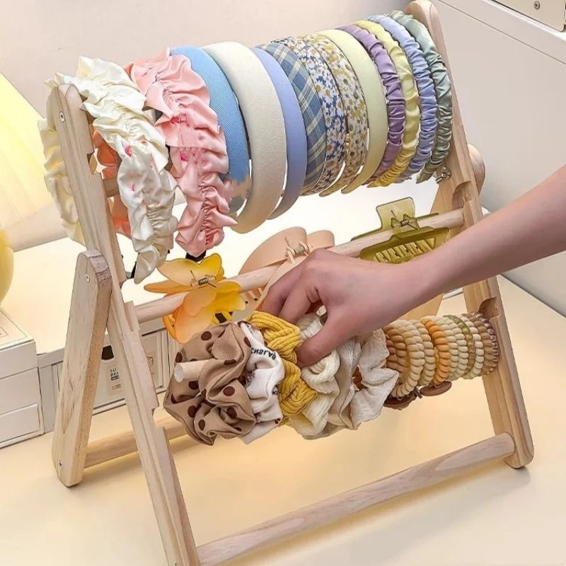 Présentoir en bois pour boucles d'oreilles et bijoux Nesty - Étagère pliante avec bandeaux, chouchous et pinces à cheveux, main qui saisit un chouchou