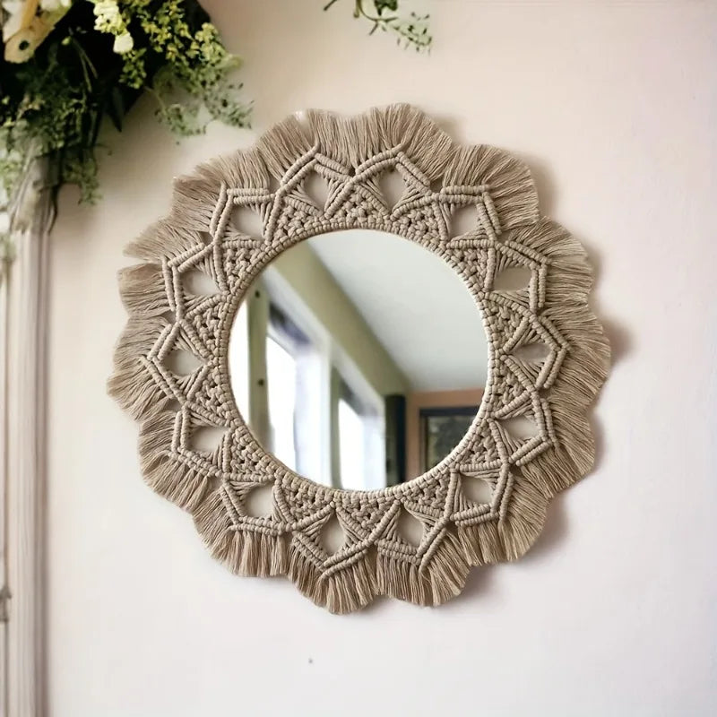 Miroir mural rond en macramé façon mandala, motif triangulaire tressé et franges, suspendu près d'un bouquet de fleurs blanches - Nesty