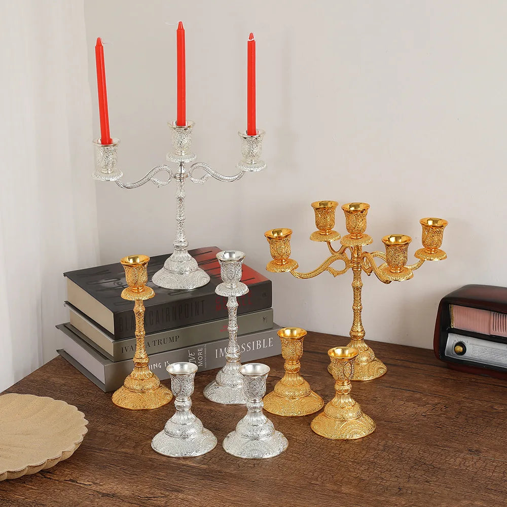 Duo de bougeoirs en métal Nesty - Chandeliers et bougeoirs dorés et argentés avec bougies rouges et blanches allumées, table en bois avec livres et radio vintage