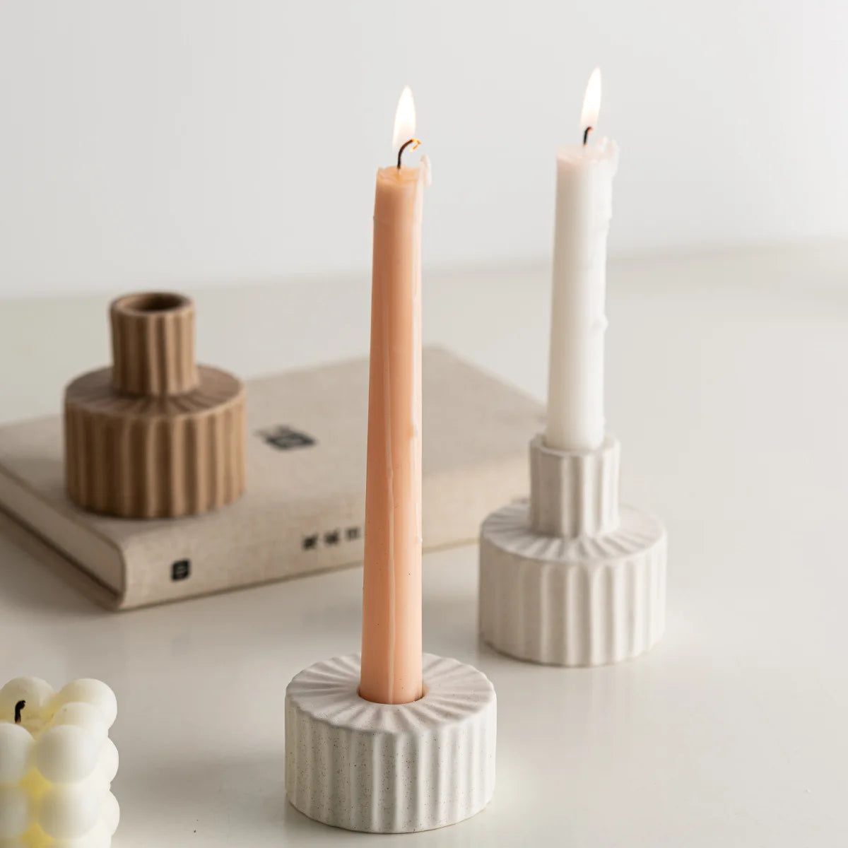 Duo de bougeoirs céramique nordique godronnés blancs, avec bougies rose et blanche allumées, sur table près de livres - Nesty