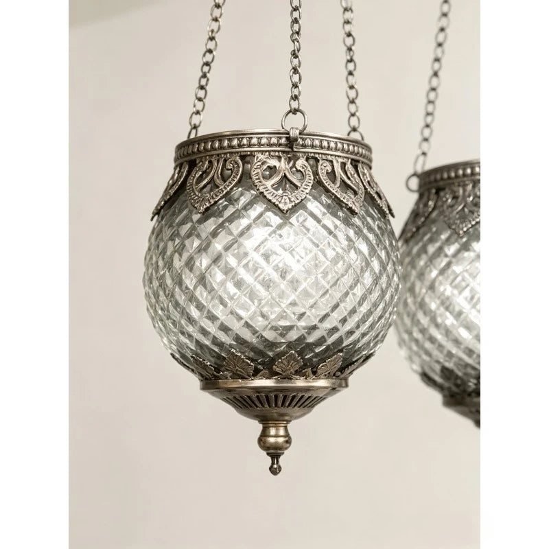 Trio de photophores suspendus en verre Nesty - Gros plan sur une lanterne en verre facetté argenté à ornements métalliques