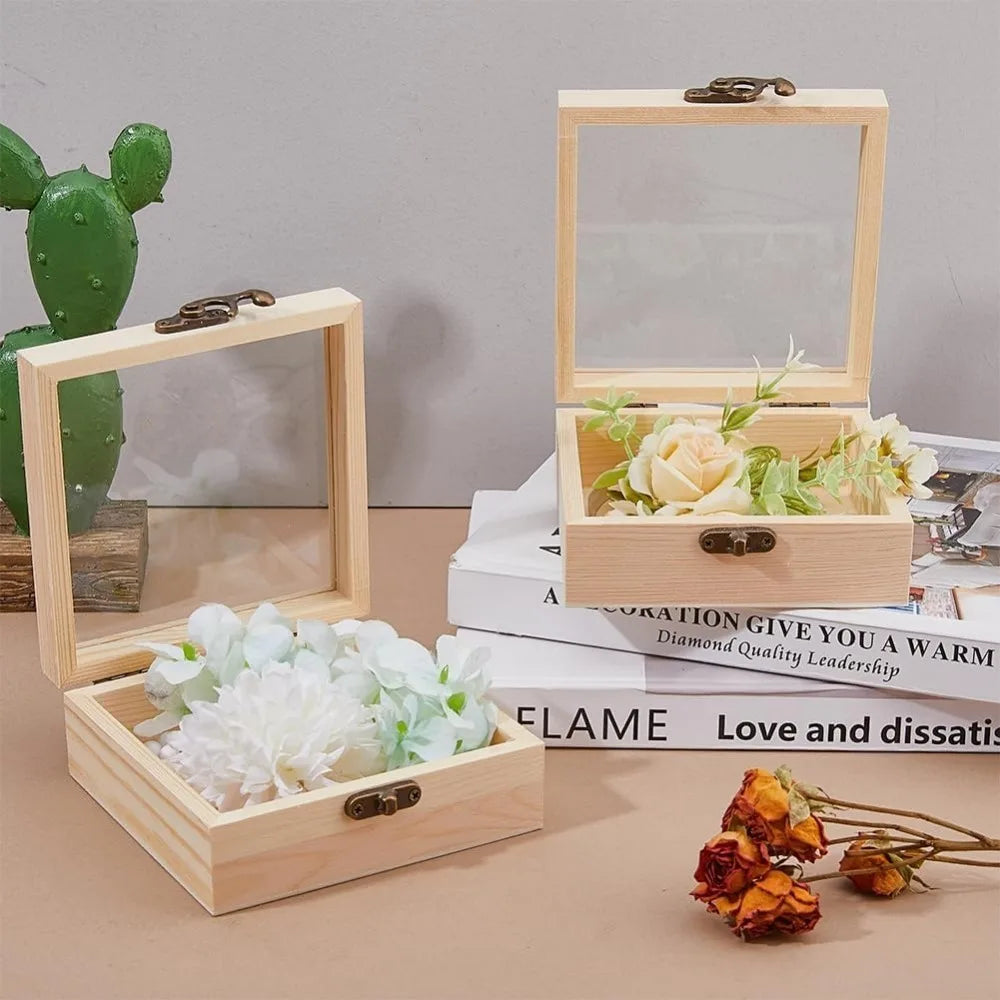 Boîte en bois à couvercle vitré Nesty - Garnie de fleurs blanches et d'une rose crème, posée sur des livres