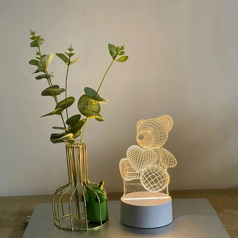 Veilleuse LED ours en acrylique Nesty - Allumée près d'un vase en verre doré