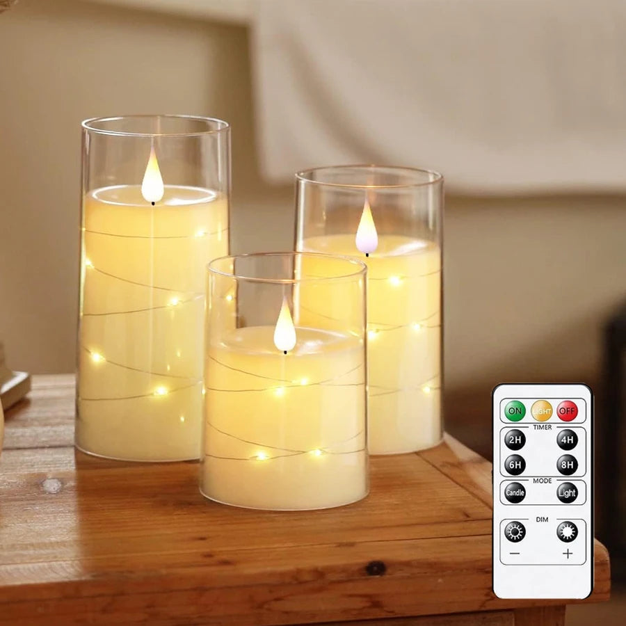Bougie LED avec guirlande étoilée intégrée, télécommande et minuterie Nesty, trois bougies LED en cire dans un cylindre en verre, guirlande lumineuse intégrée en spirale, télécommande à côté, sur table en bois