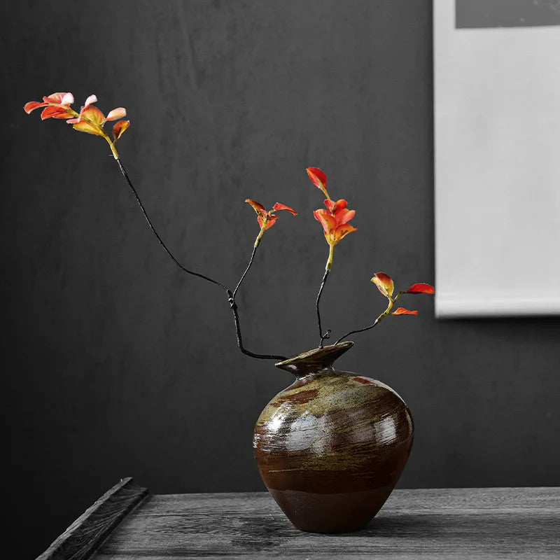 Vase en céramique brute, petit format esprit zen Nesty, vase bulbe en céramique brun foncé garni de branches à fleurs oranges, sur table sombre