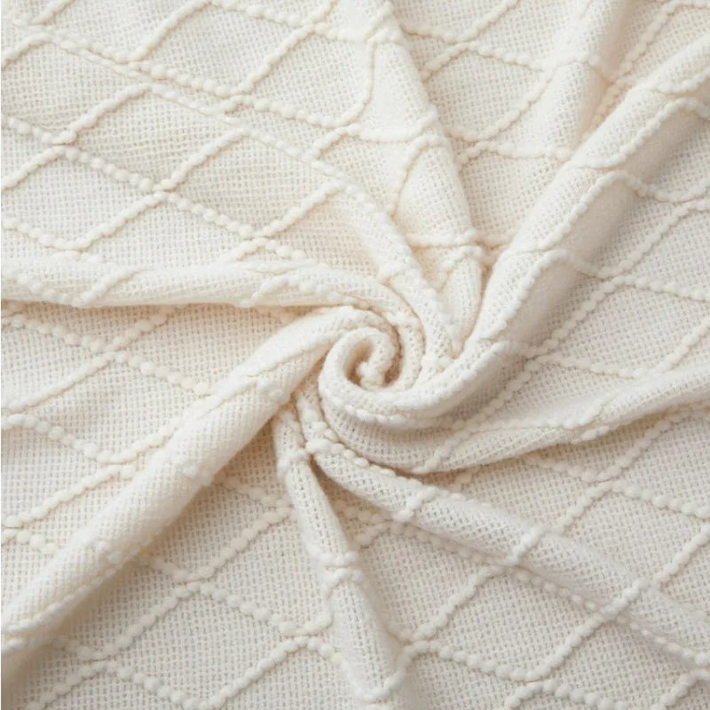 Plaid tricoté bohème blanc cassé Nesty - Gros plan tourbillonnant sur la texture tricotée à motif losanges