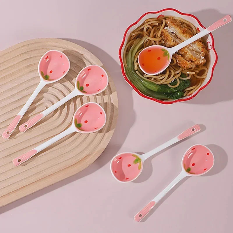 Cuillère en céramique fraise, modèle mignon Nesty, cuillères sur une planche en bois et une cuillère posée dans un bol de nouilles avec sauce