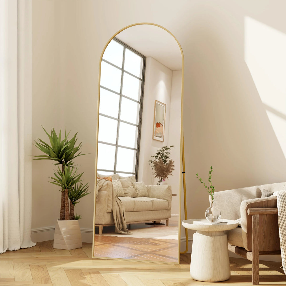 Miroir psyché incurvé Nesty - Cadre doré, reflet d'un canapé beige et d'une table basse fleurie