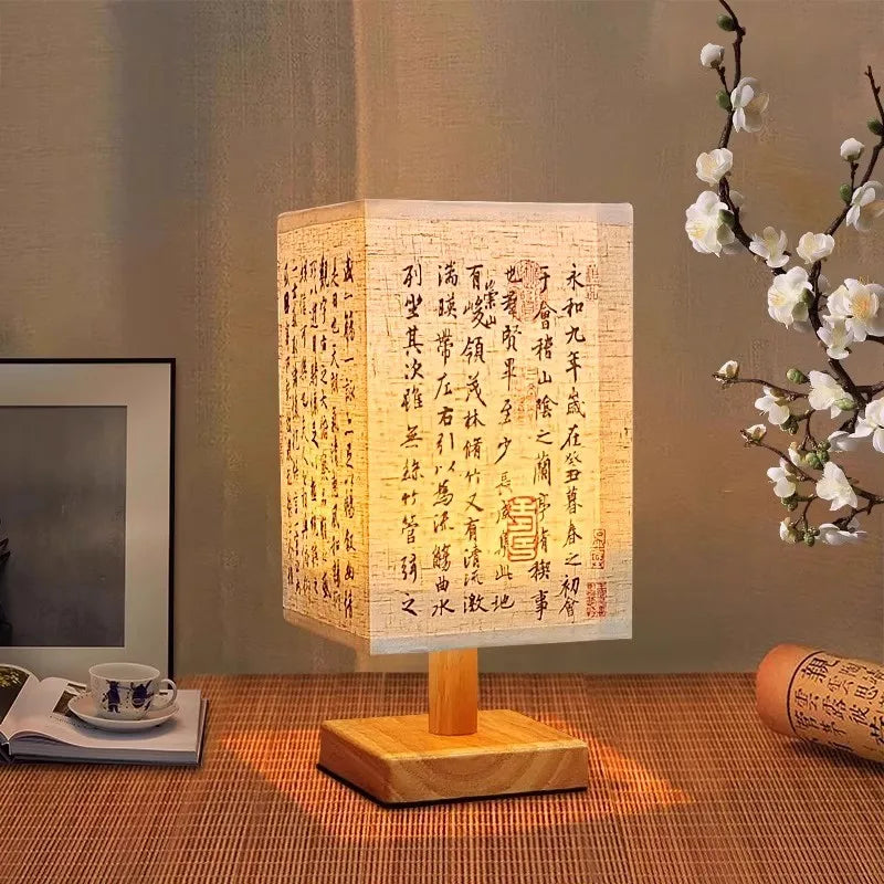 Lampe de table en tissu Nesty - Posée sur un set en raphia près d'une tasse et de fleurs de prunier blanches