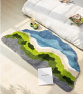 Tapis de chevet en forme libre représentant un paysage de rivière bleue serpentant entre des collines vertes et grises, posé au sol près d'un lit et d'un plateau petit-déjeuner.