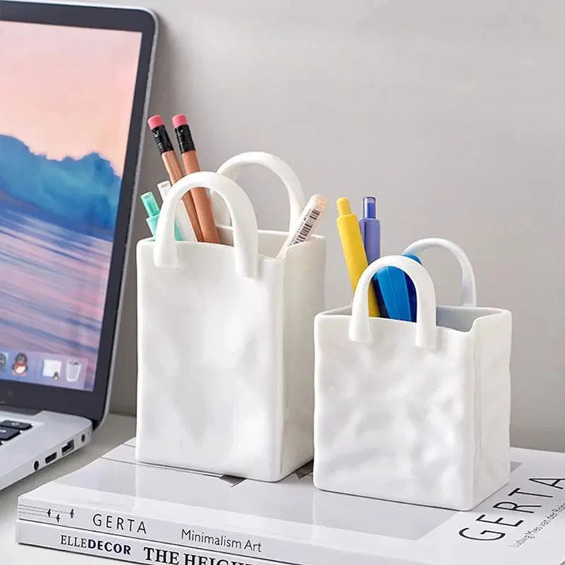 Mini vase blanc forme sac à main, fleurs séchées - Nesty - Deux tailles utilisées comme pots à crayons avec stylos et ciseaux, posés sur des livres près d'un ordinateur portable
