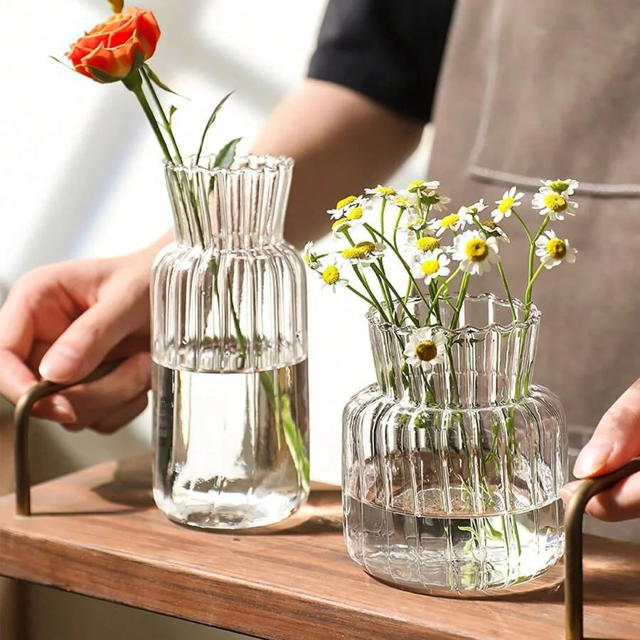 Vase en verre transparent strié, mini format rétro Nesty, deux formes côtelées tenues en main, l'une garnie d'une rose orange, l'autre de marguerites blanches