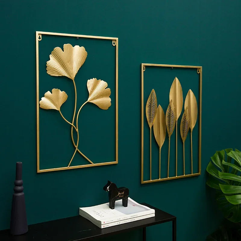 Pendentif mural en fer forgé à motif végétal Nesty, deux cadres dorés à motifs de gingko et de feuilles longues sur un mur vert foncé, avec vase et console noire
