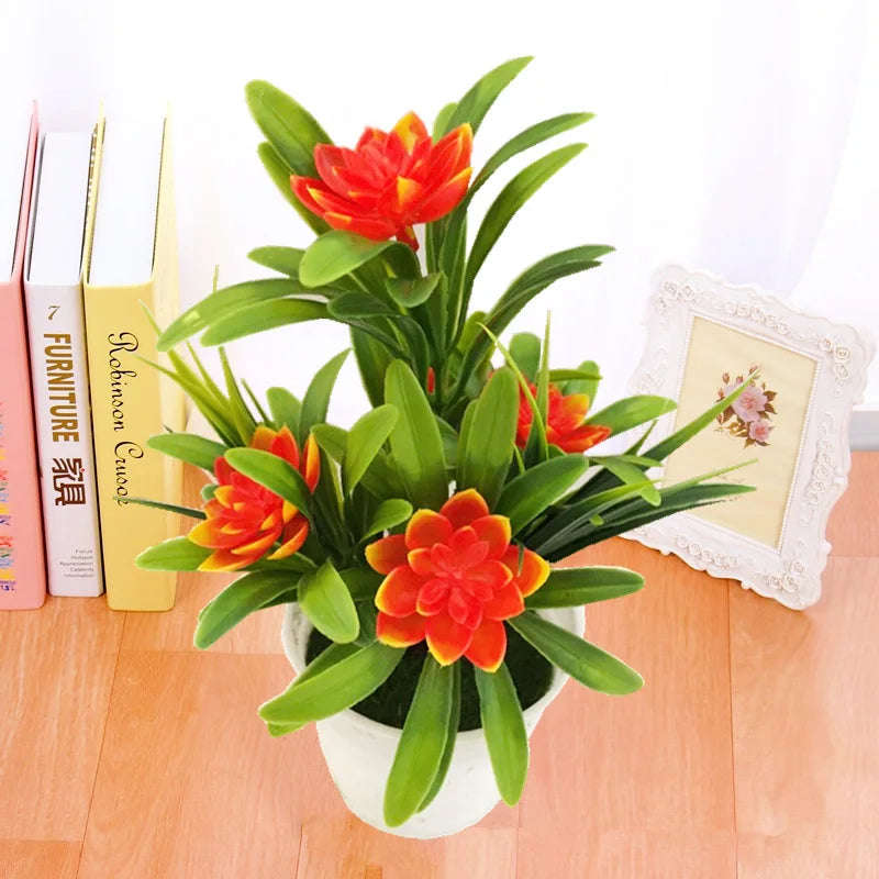 Pot de fleurs artificielles lotus Nesty - Coloris orange et rouge, posé près de livres