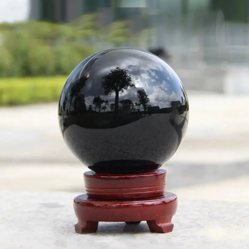Sphère en obsidienne naturelle Nesty - Posée sur un socle en bois à l'extérieur