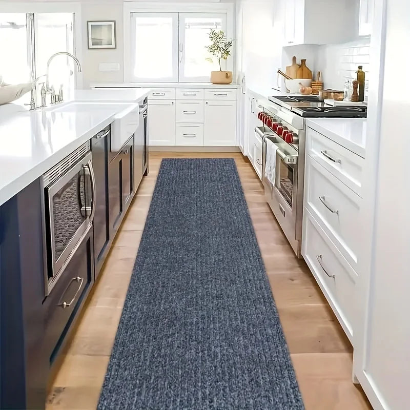Tapis autocollant en rouleau — coloris uni - Nesty, chemin de cuisine bleu marine posé entre un îlot et une cuisinière dans une cuisine blanche