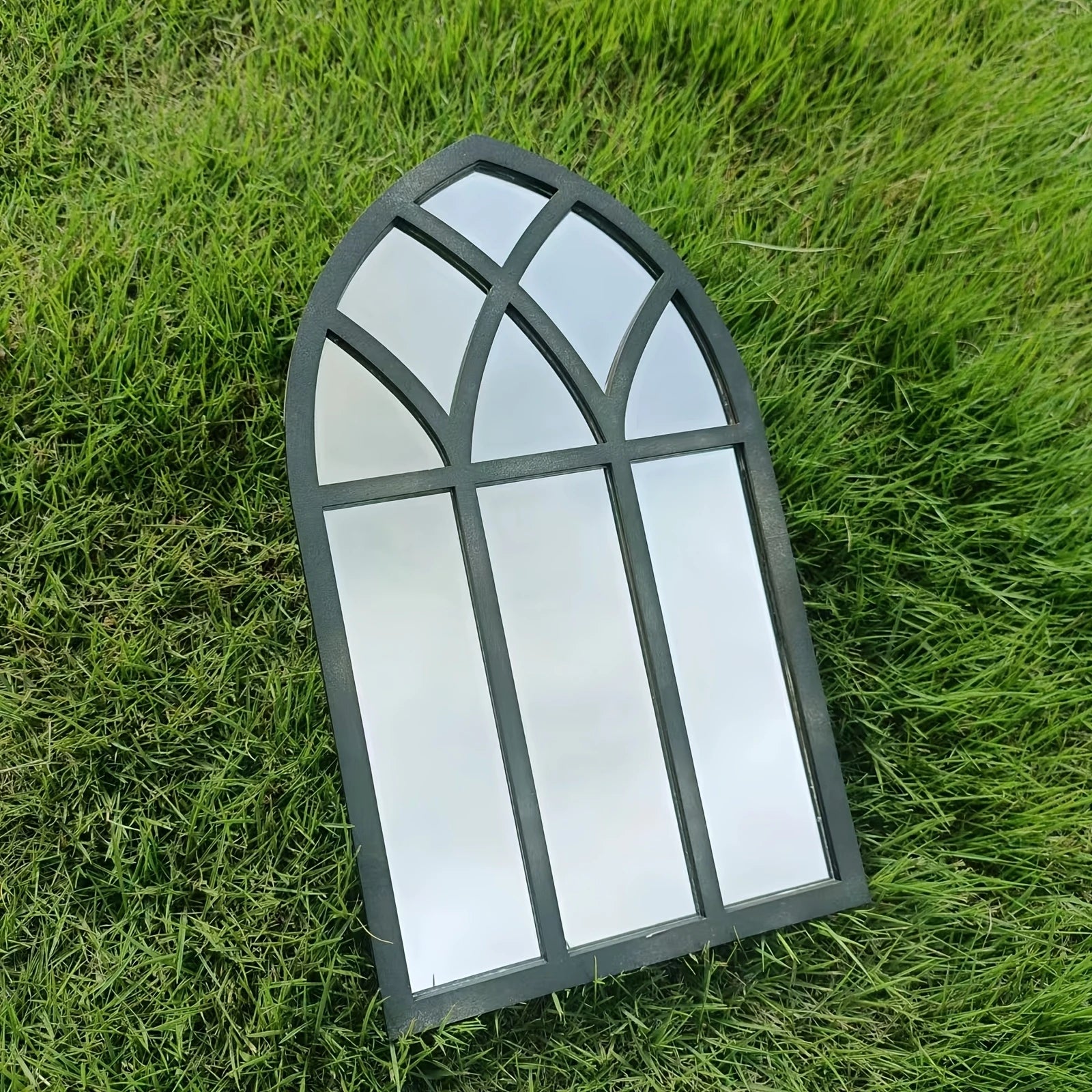 Miroir fenêtre en bois et acrylique Nesty - Format simple, posé en angle sur l'herbe, reflet du ciel et d'un arbre