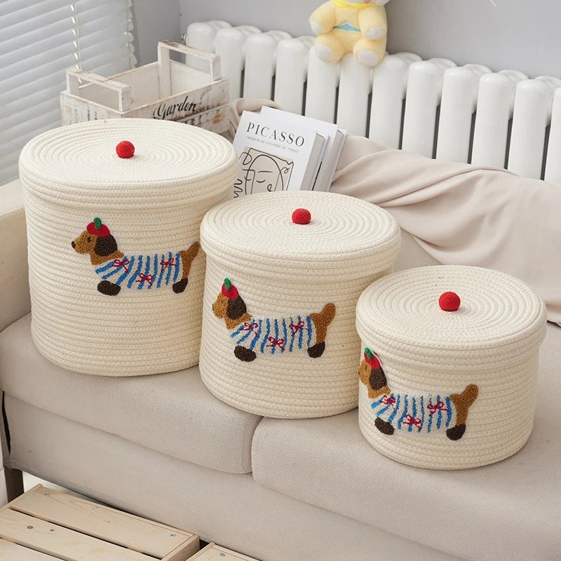 Panier de rangement pliable en corde de coton, grande capacité Nesty, trois tailles sur un canapé avec peluche ourson et livre Picasso