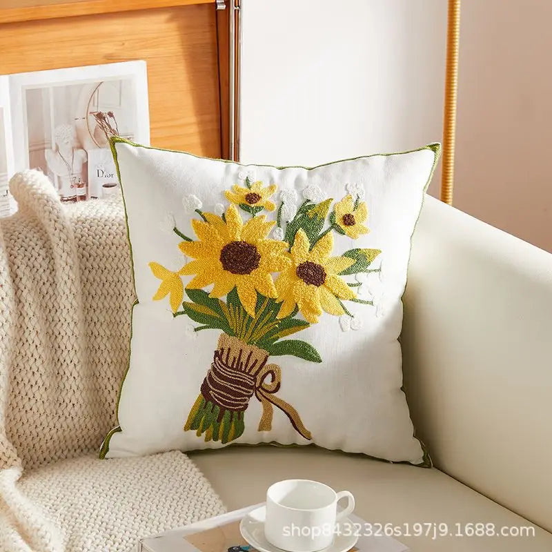 Housse de coussin en coton et lin, broderie pissenlit Nesty, housse de coussin blanche brodée d'un bouquet de tournesols noué d'un ruban, posée sur canapé avec plaid en maille