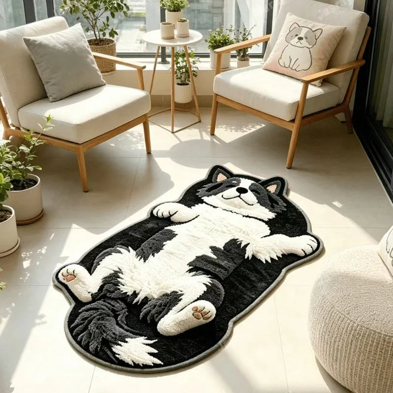 Tapis en forme de husky noir et blanc allongé sur le dos, posé sur une terrasse carrelée entre deux fauteuils en bois clair.