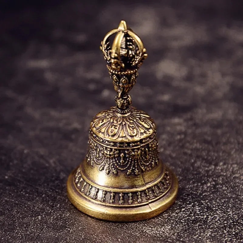 Clochette en bronze vintage Nesty - Vue de face sur fond texturé sombre