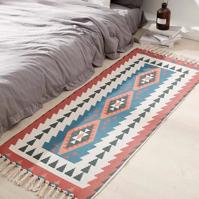 Tapis en coton et lin tissé main — motif berbère - Nesty, variante motif géométrique rouge, bleu et écru façon kilim, posée au pied d'un lit