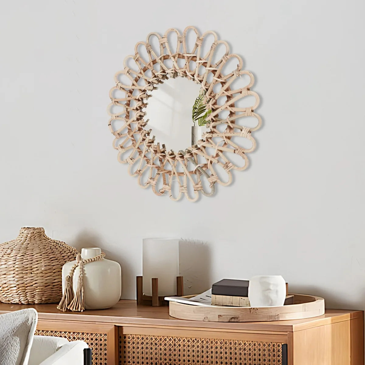 Miroir rond en rotin tressé Nesty - Accroché au-dessus d'un buffet en bois avec vase et bougie