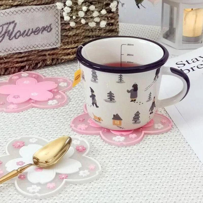 Dessous de verre en silicone fleurs de cerisier rose, sous une tasse de thé décorée, panier en osier et lanterne en arrière-plan - Nesty