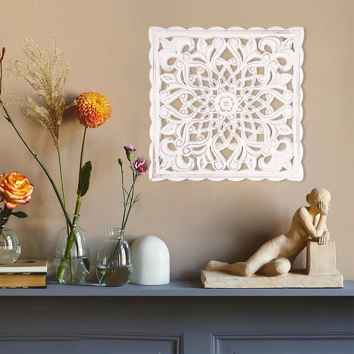 Panneau mural ajouré en bois à motif floral Nesty, panneau carré blanc accroché sur un mur beige, avec vases de fleurs et statuette