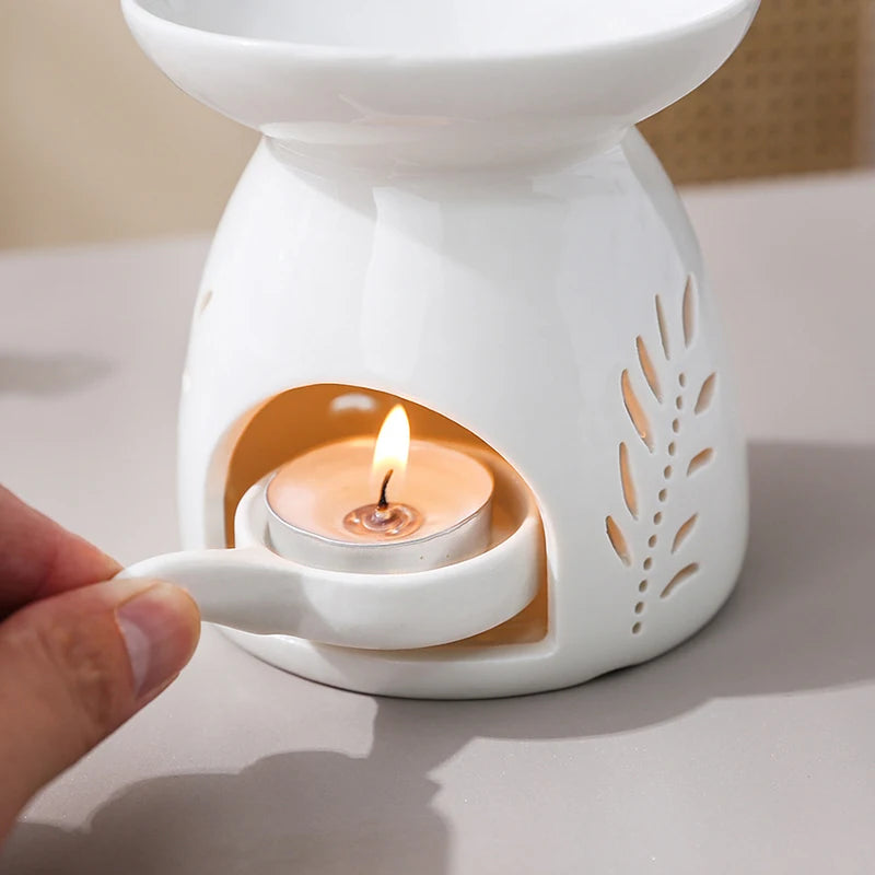 Brûle-parfum en céramique ajourée Nesty - Gros plan sur le motif feuilles découpées et la bougie chauffe-plat allumée