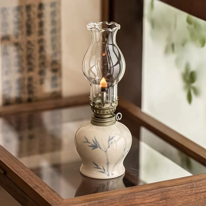 Lampe à pétrole en céramique peinte à la main motif bambou, globe en verre allumé, posée sur un plateau miroir en bois - Nesty