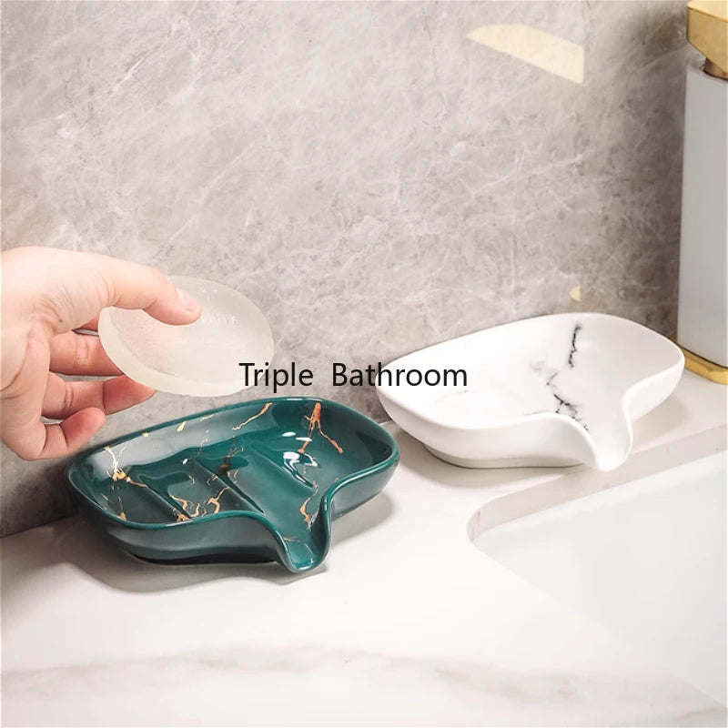 Porte-savon en céramique effet marbre vert et blanc, main tenant un porte-savon en silicone translucide, sur un plan de vasque - Nesty