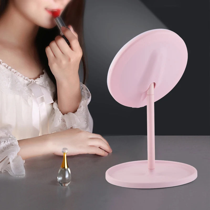Miroir de voyage ovale rose sur pied avec plateau, femme se maquillant en arrière-plan - Nesty